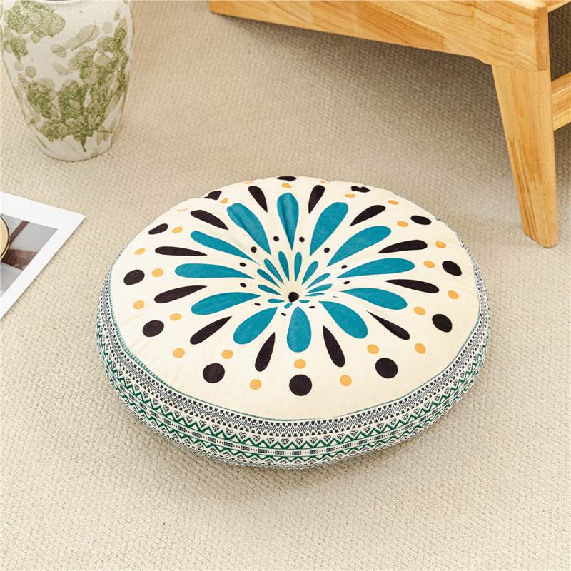 Decorative round pillow with blue and black floral pattern on a beige floor.
