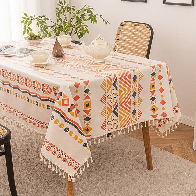 Dining table with a patterned tablecloth, chair, and decorative items.