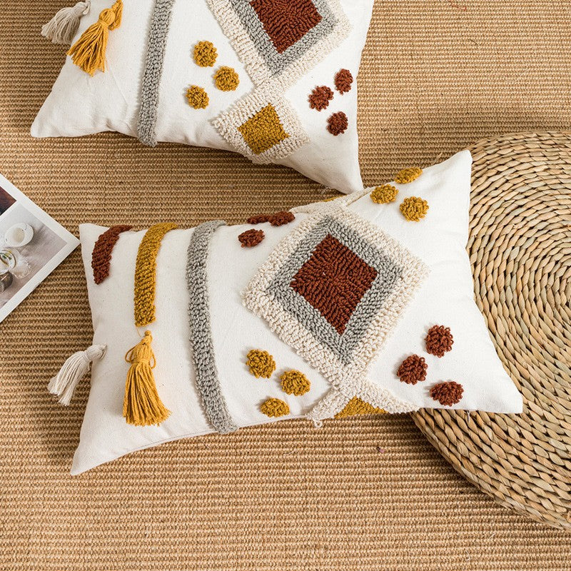 Decorative pillows with textured patterns and tassels on a woven surface