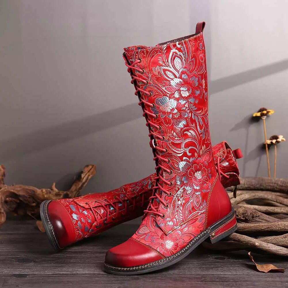 Red embroidered boots on a wooden surface with a neutral background