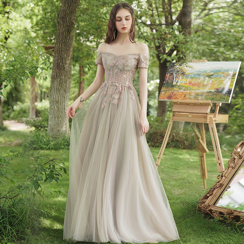 Woman in a beige evening gown standing in a garden with a painting easel and canvas in the background.