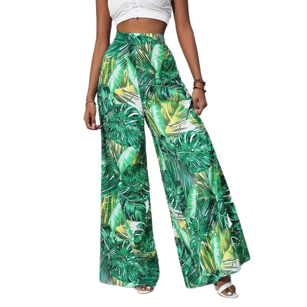 Green tropical leaf patterned pants worn by a person on a white background