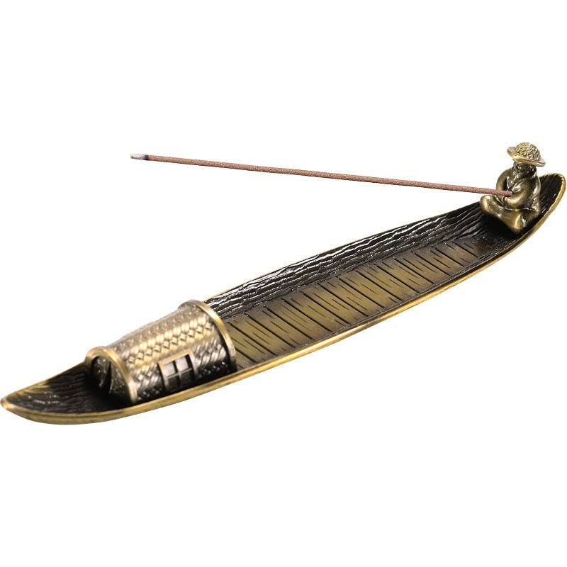 Decorative incense holder shaped like a longboat with a figure on a white background