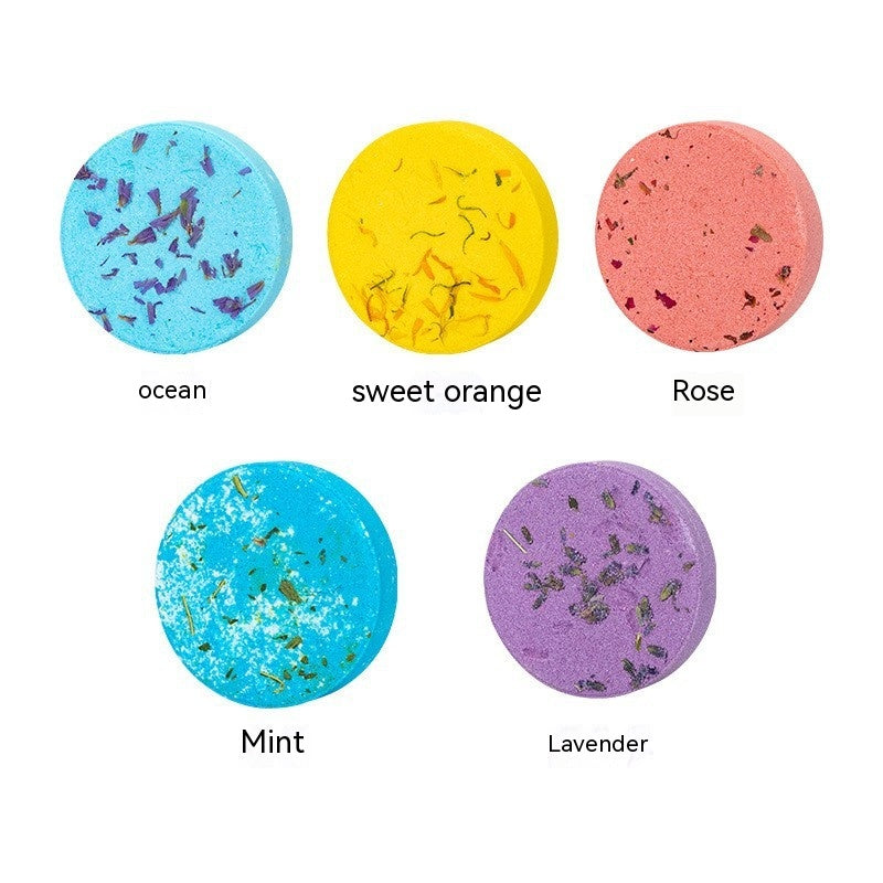 Five bath bombs in different colors with labels below them on a white background
