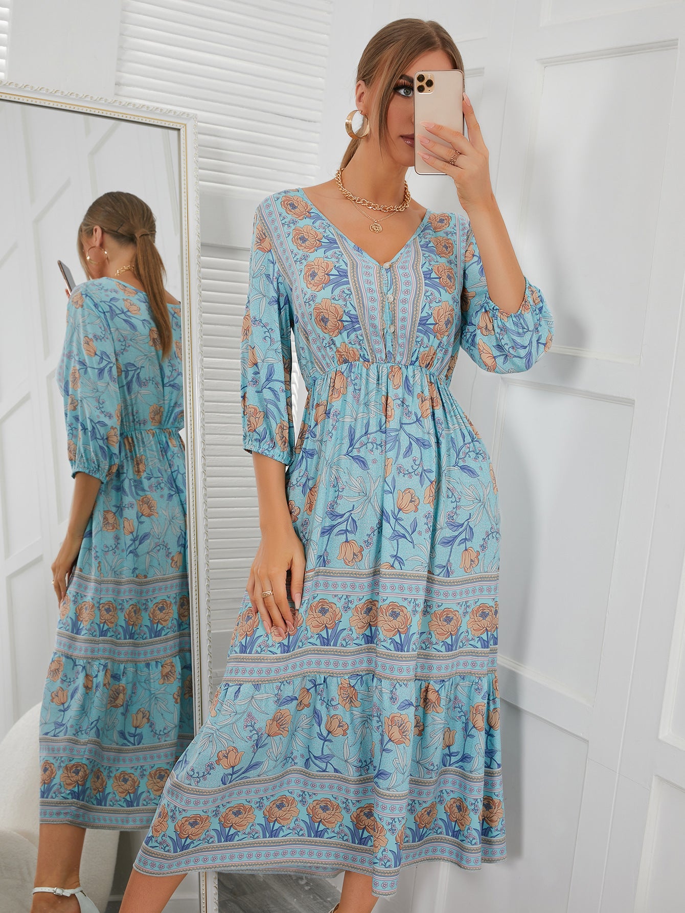 Woman wearing a blue floral dress taking a mirror selfie.