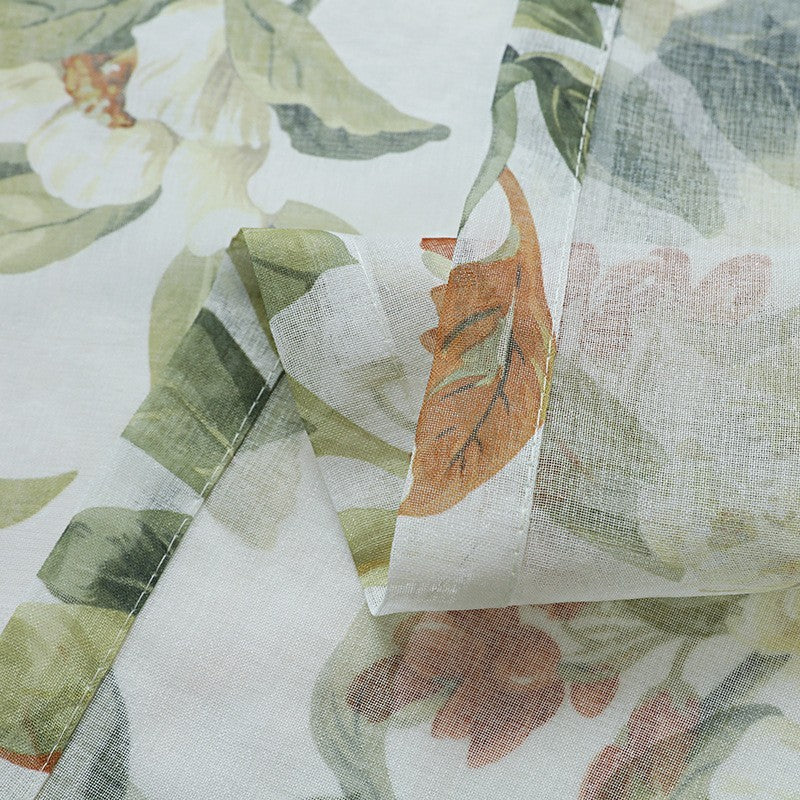 Close-up of floral fabric with green leaves and orange flowers on a white background
