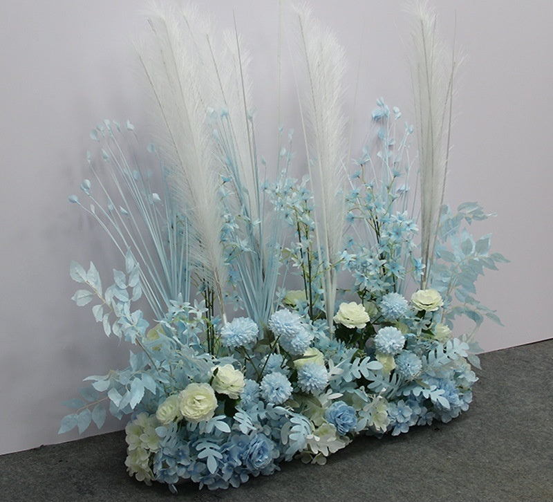 Decorative floral arrangement with blue and white flowers on a gray surface.