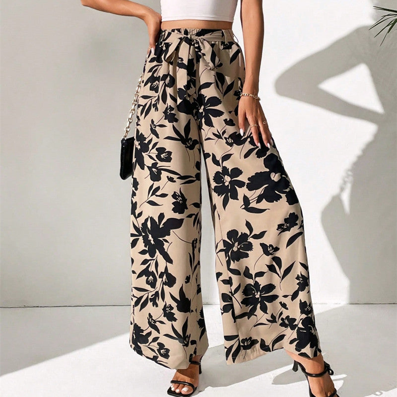 Beige pants with black floral pattern worn by a person on a white background