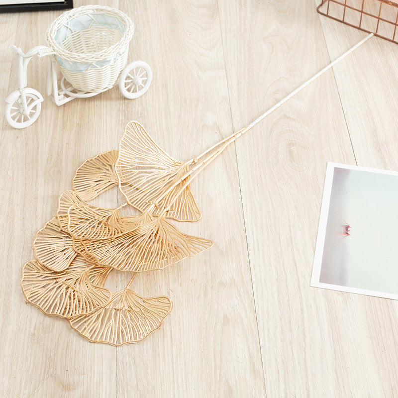 Decorative leaf-shaped items on a wooden surface with a small white cart and photo frame in the background.