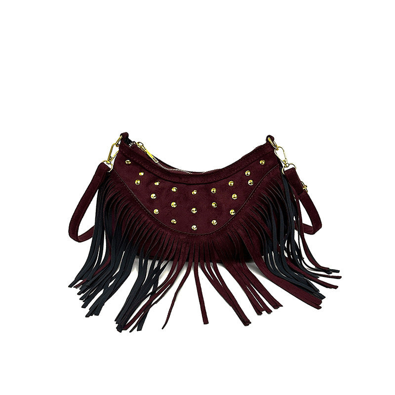 Burgundy handbag with gold studs and black fringe on a white background
