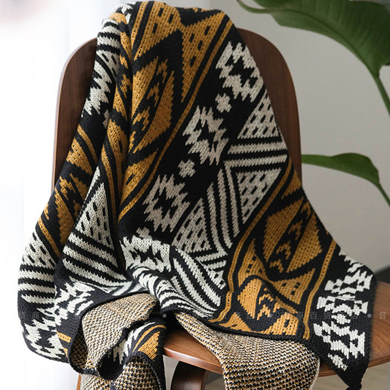 Knitted blanket with geometric pattern draped over a chair