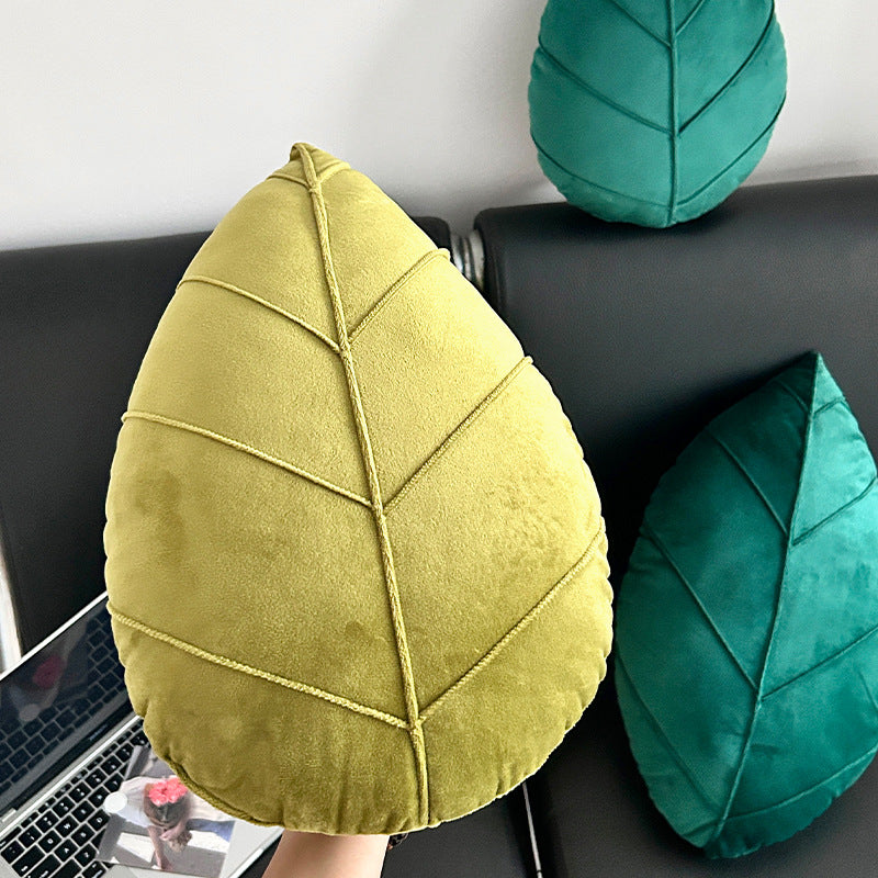 Leaf-shaped cushions in yellow and green on a sofa with a laptop.