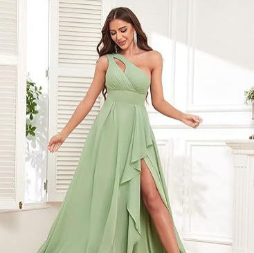 Woman wearing a light green one-shoulder dress with a slit, standing in a bright room.