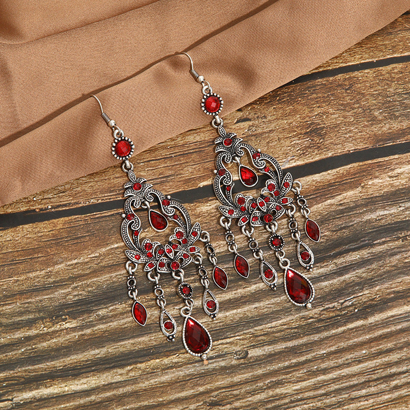 Ornate earrings with red gemstones on a wooden surface