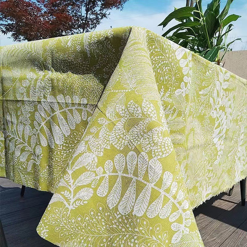 Green and white patterned tablecloth on an outdoor table with plants in the background