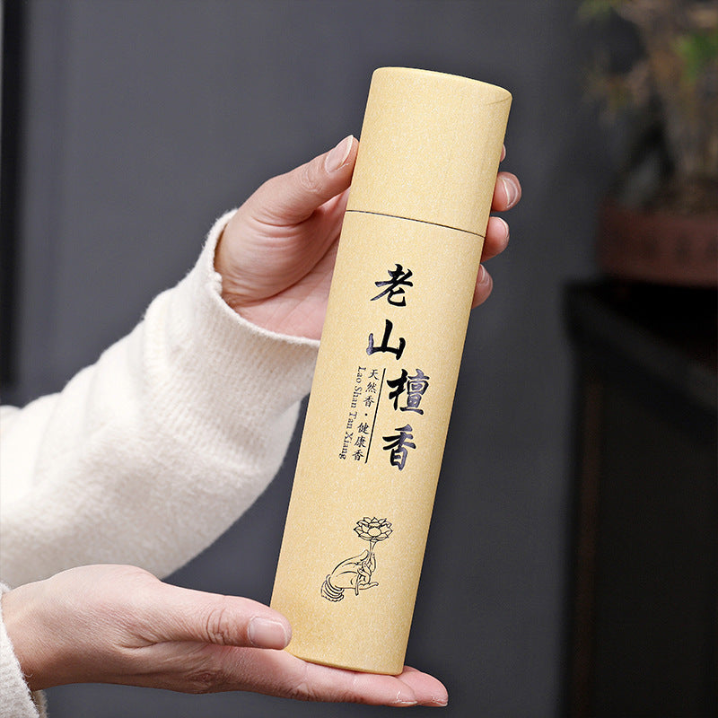 Hand holding a cylindrical beige product with text and design against a neutral background