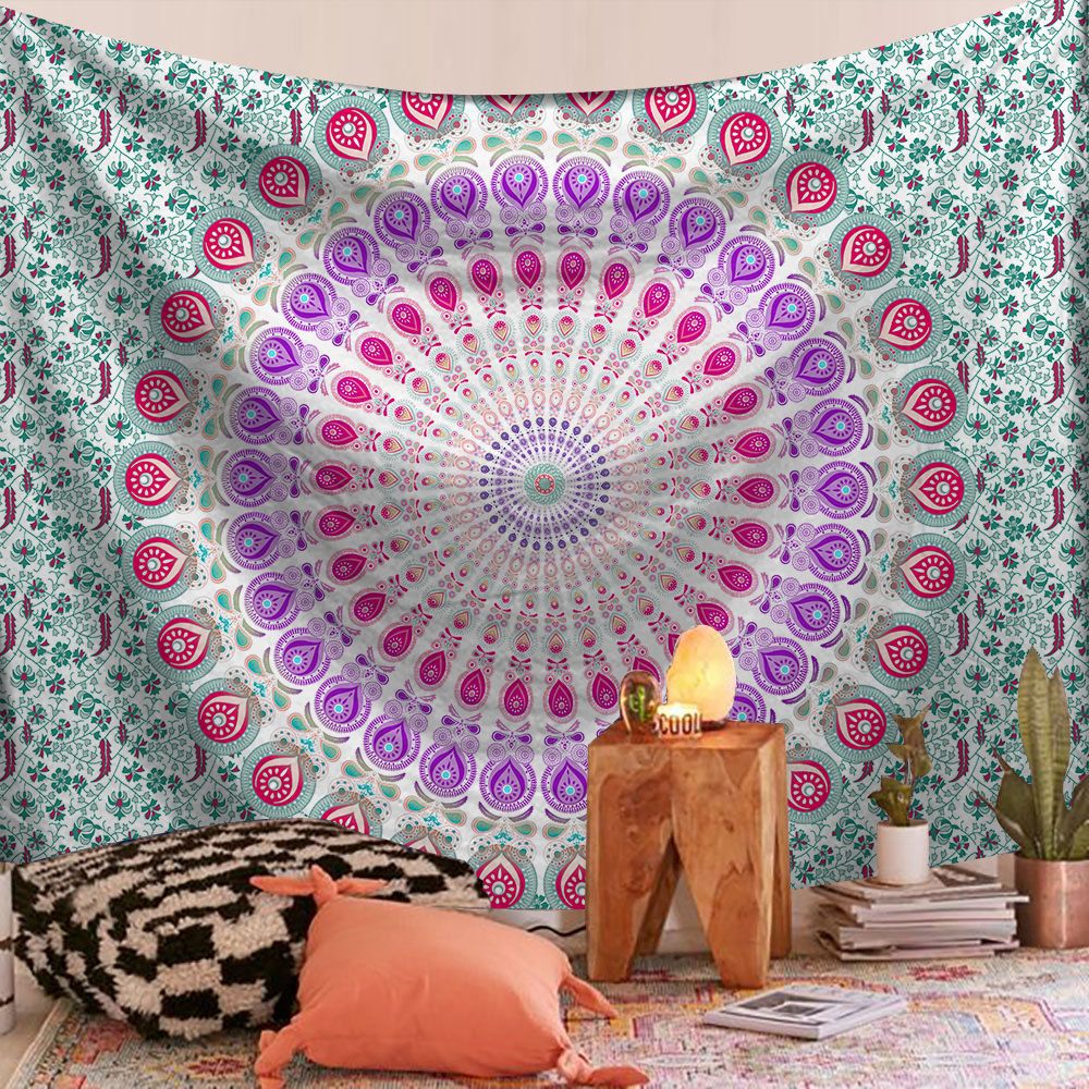 Mandala tapestry with pink and purple patterns hanging on a wall in a room.