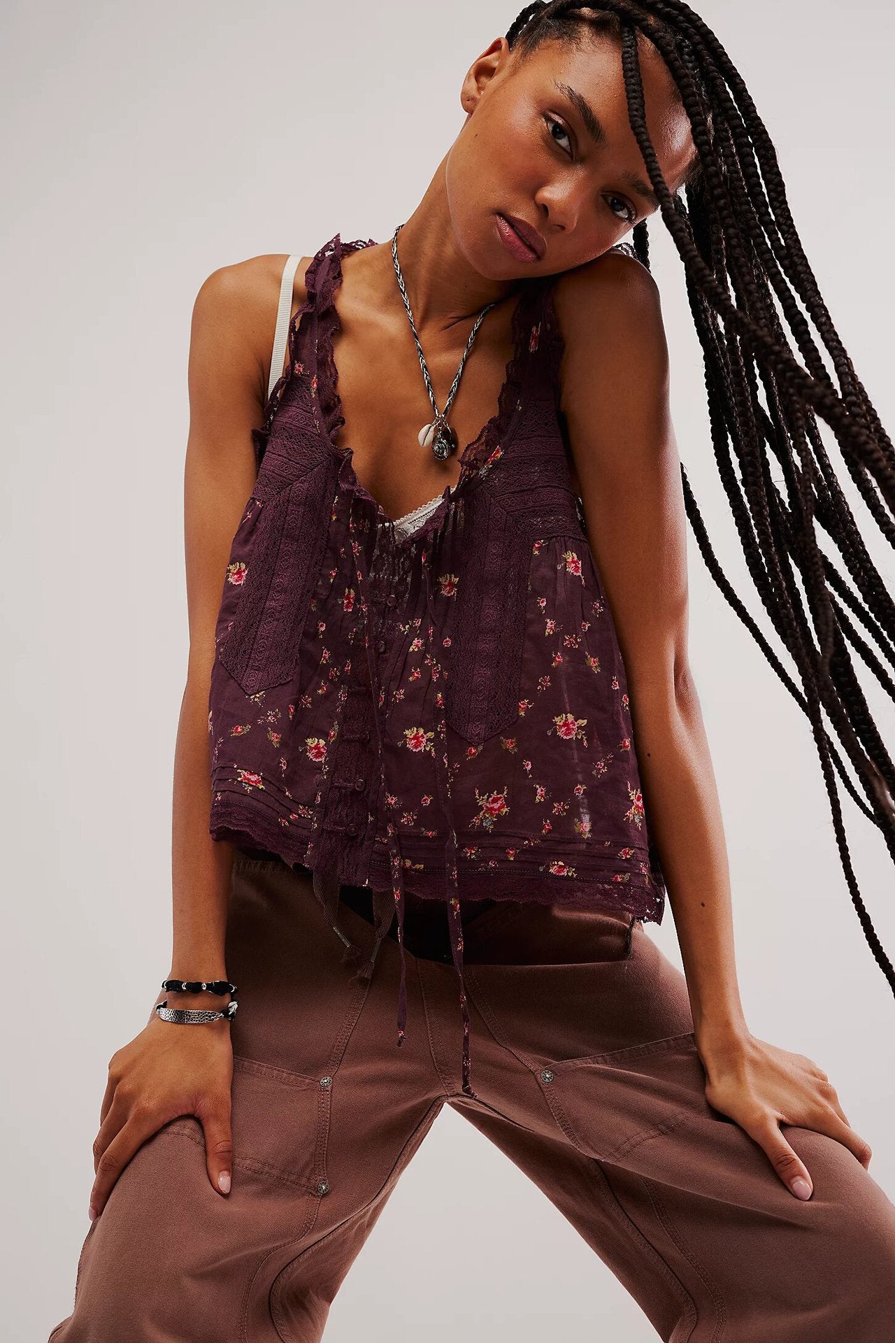 Woman wearing a patterned top and brown pants against a plain background
