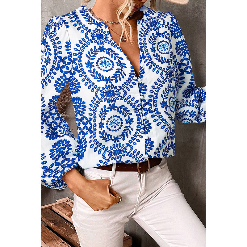 Woman wearing a blue and white patterned blouse with white pants against a neutral background