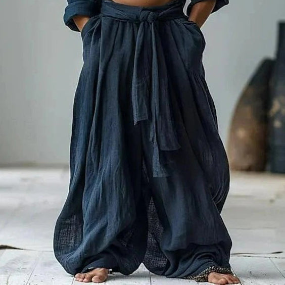 Person wearing dark blue harem pants with a minimal background