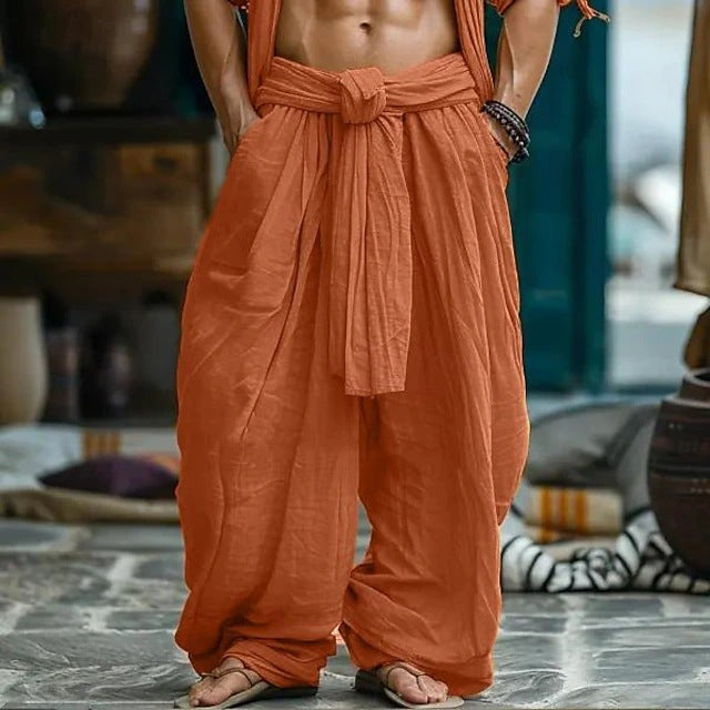 Person wearing orange traditional attire standing on a stone floor with a blurred background