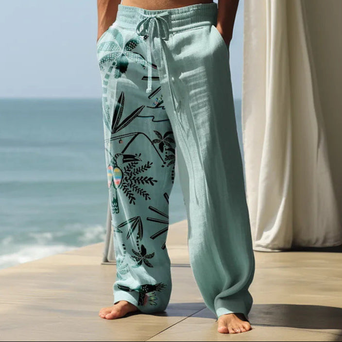 Person wearing light blue floral-patterned pants standing on a wooden deck with ocean view.