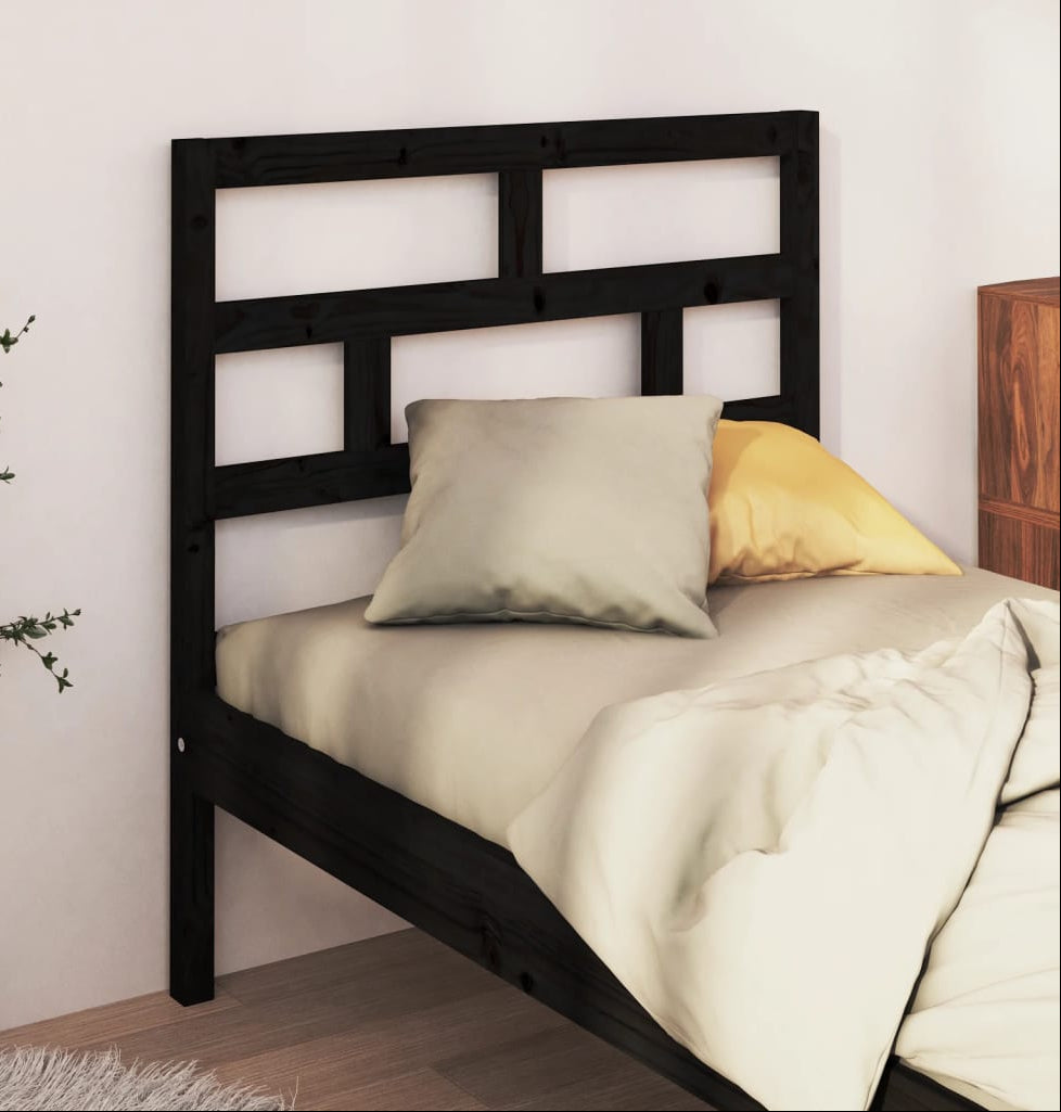 Black metal bed frame with bedding and pillows against a white wall.