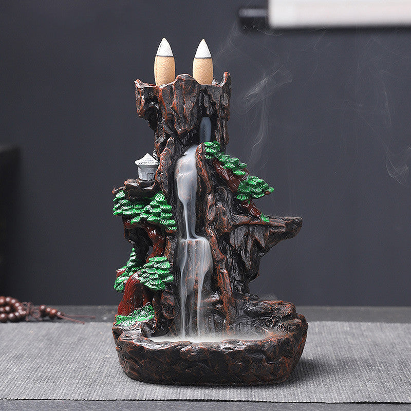 Decorative incense burner shaped like a mountain with waterfalls and candles on top.