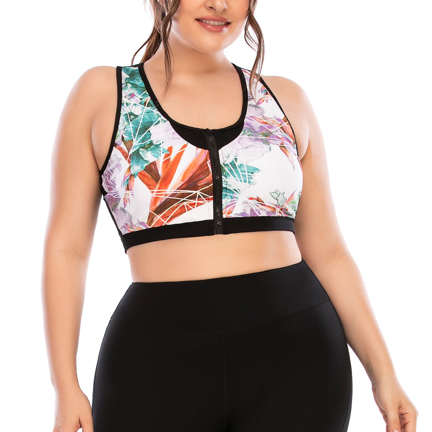 Woman wearing a colorful leaf-patterned sports bra and black leggings on a white background