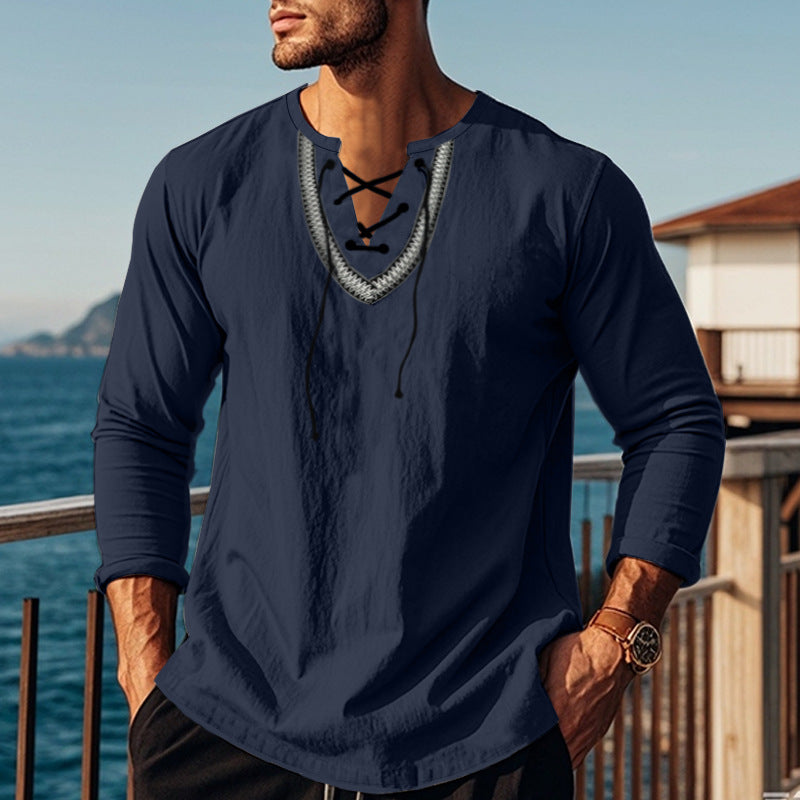 Man wearing a navy blue long-sleeve shirt with lace-up details by a waterfront.