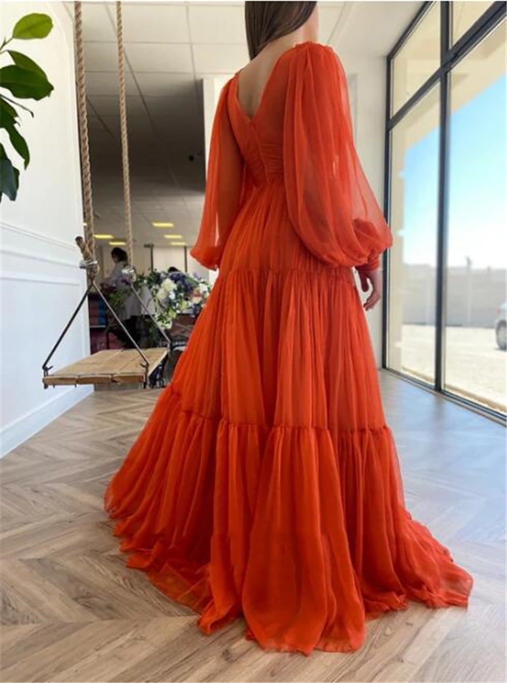 Orange dress with long sleeves and tiered skirt on a person indoors.