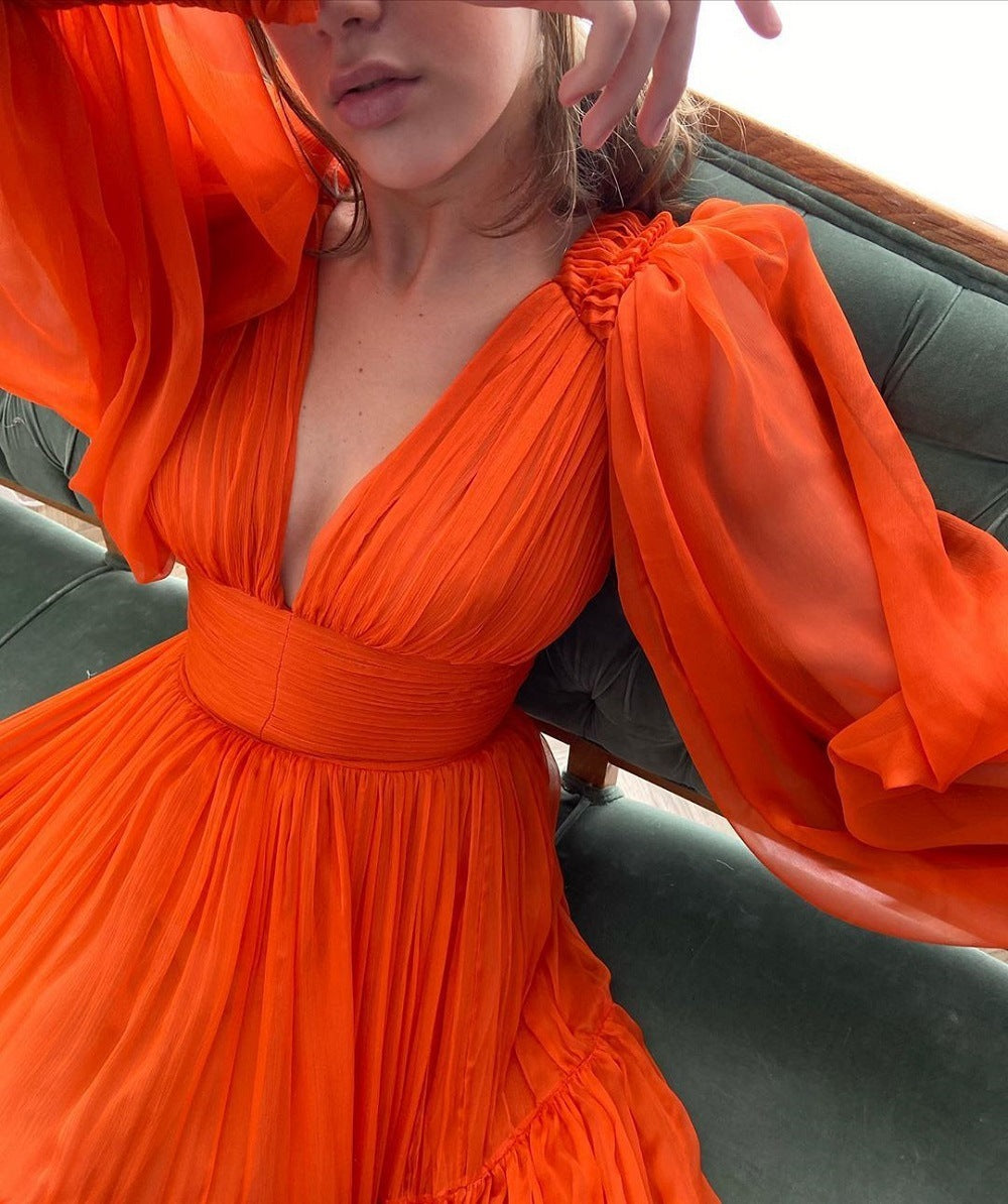 Orange dress with sheer sleeves and a floral detail on a person.