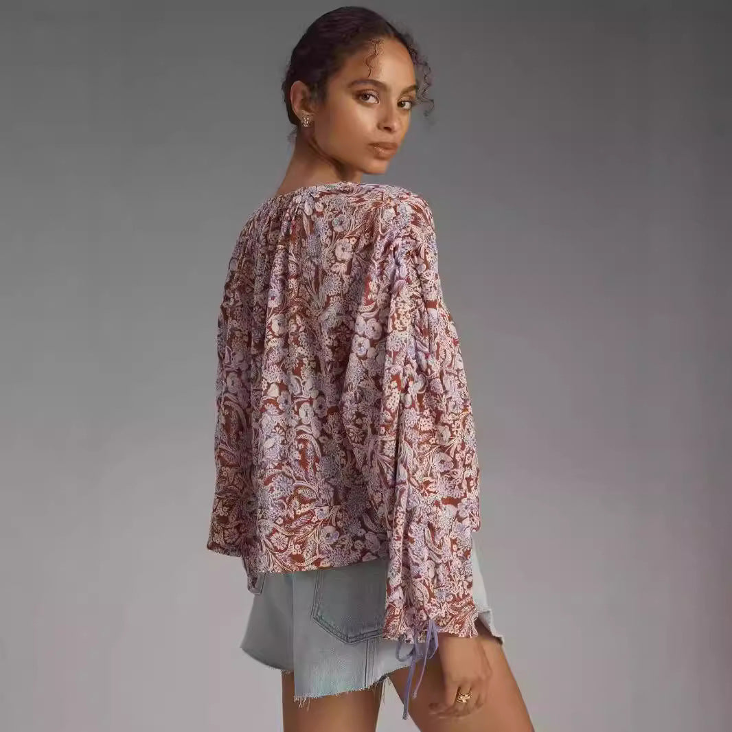 Woman wearing a patterned blouse against a gray background