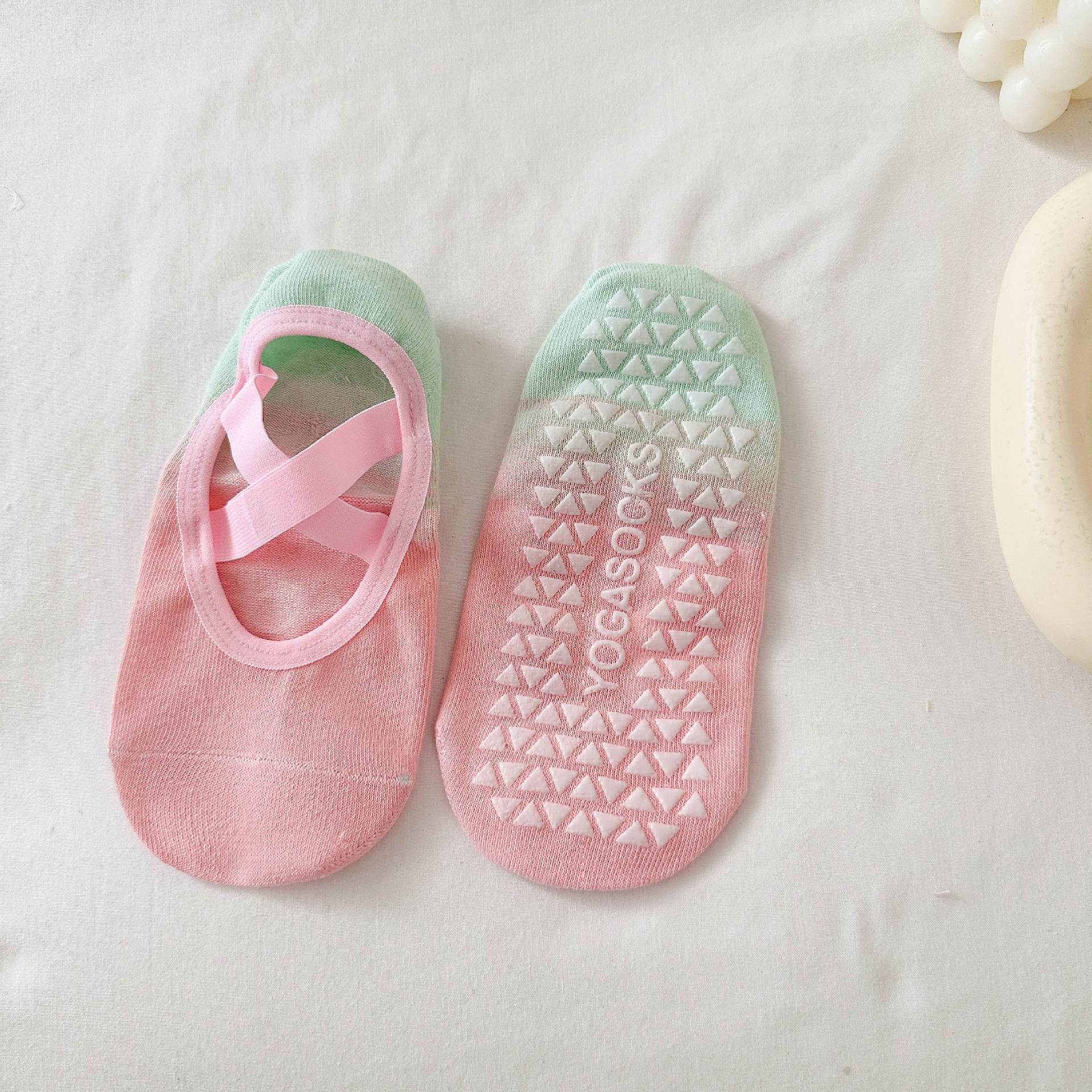 Pair of pink and green yoga socks with a pattern on a light background