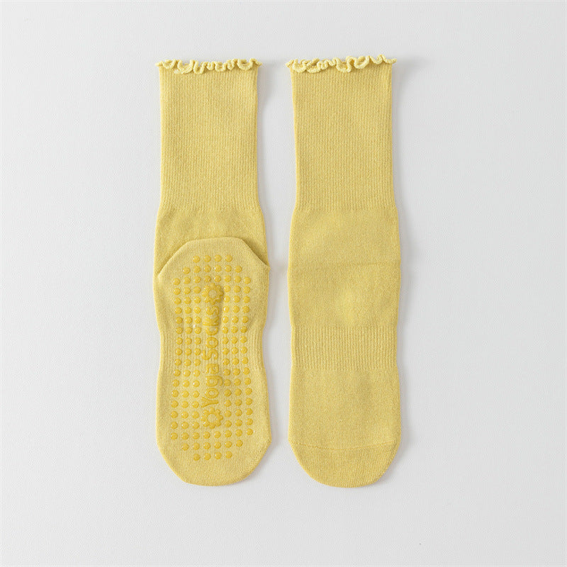 Pair of yellow socks with textured sole on a light gray background