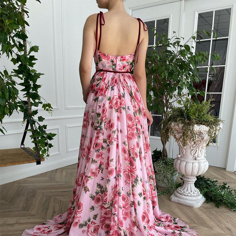 Person wearing a pink floral dress standing in a room with plants.