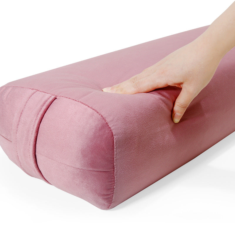 Pink cylindrical pillow with a hand touching it on a white background