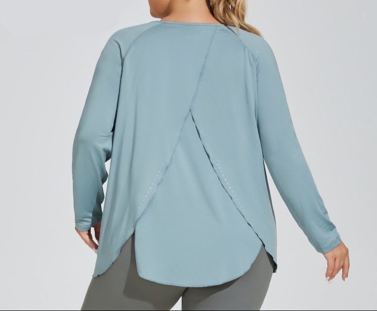 Woman wearing a light blue long-sleeve top with a design on the back, on a gray background.