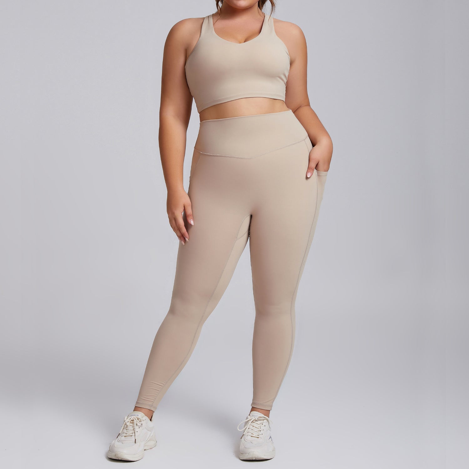 Person wearing a beige sports bra and leggings set on a plain background