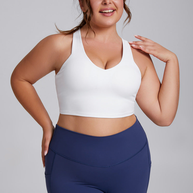 Woman wearing a white sports bra and blue leggings on a gray background
