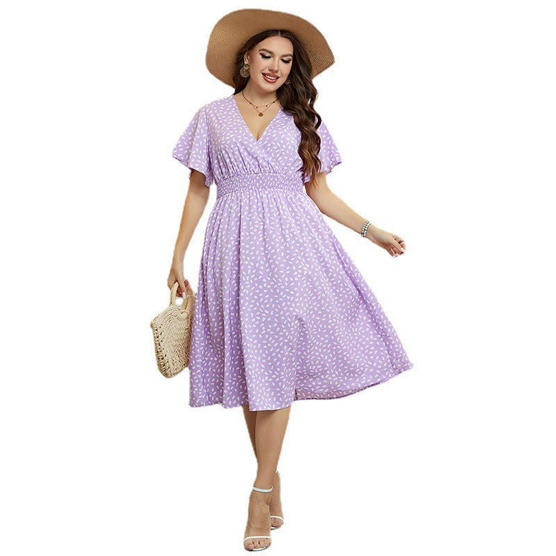 Woman wearing a purple floral dress with a straw hat and bag on a white background