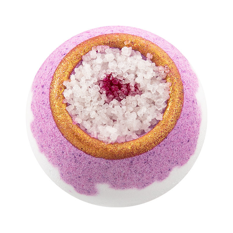 Purple bath bomb with gold rim and pink center on a white background