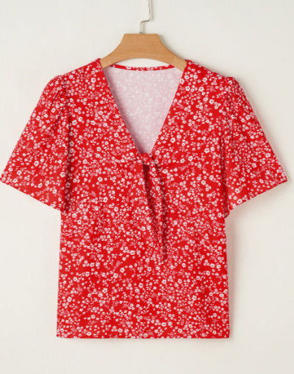 Red floral blouse on a hanger against a white background
