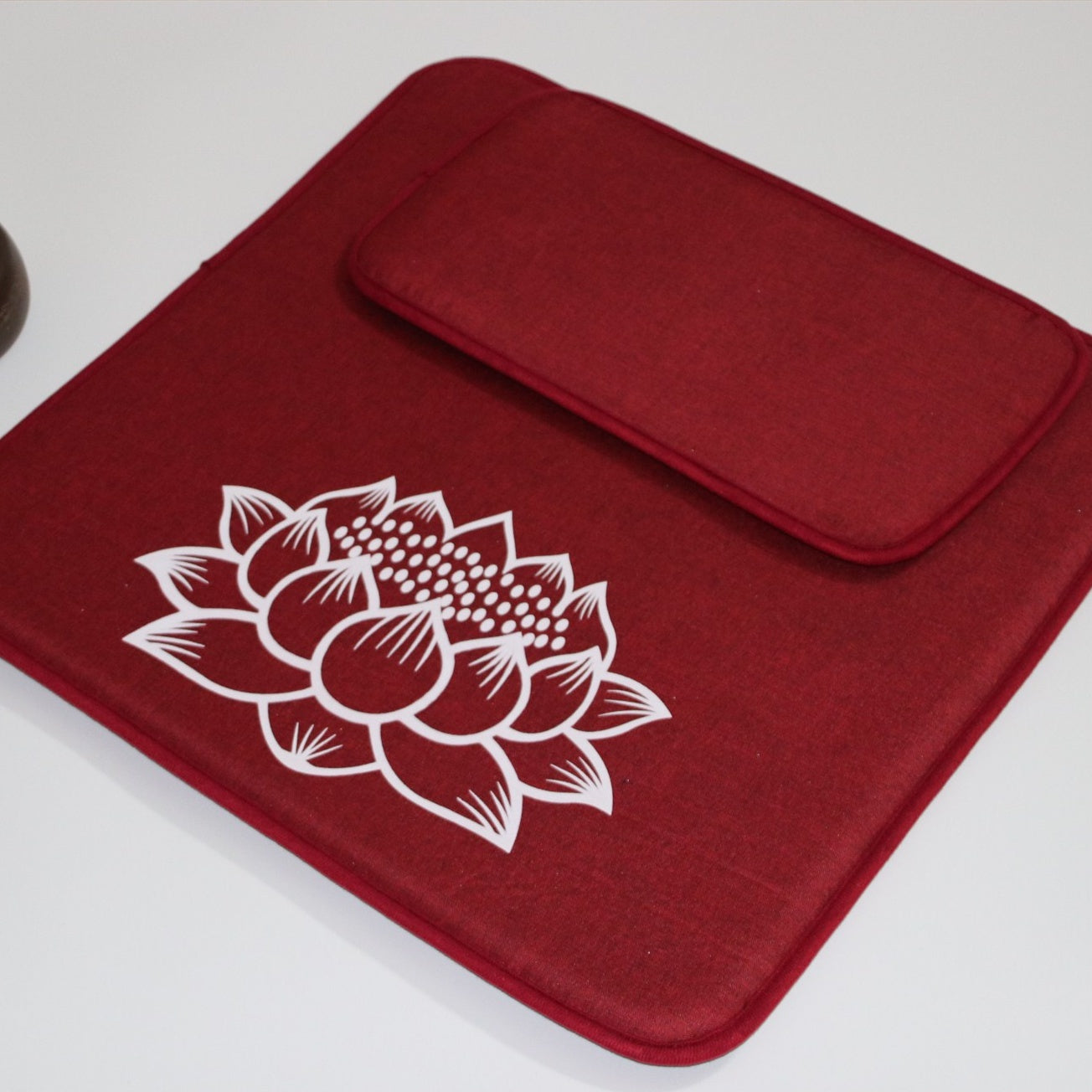 Red fabric pouch with a white lotus flower design on a light gray background