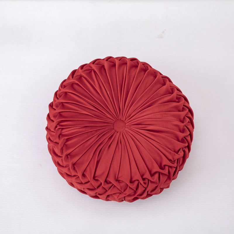 Red round pillow with pleated texture on a white background