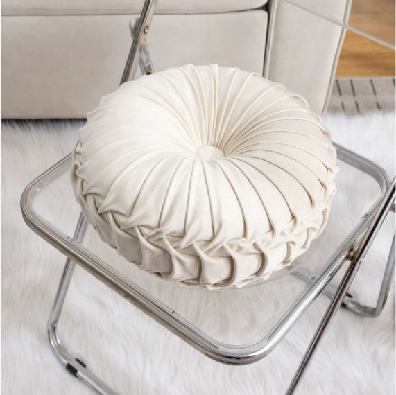 Round white cushion on a metal chair with a neutral background
