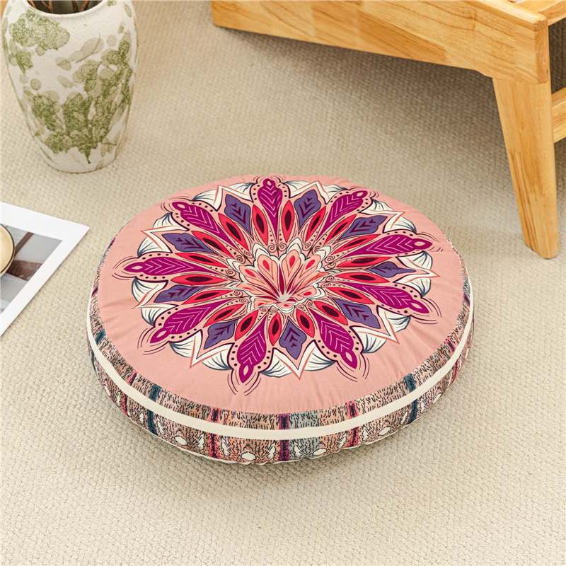 Round decorative pillow with mandala pattern on a beige floor.