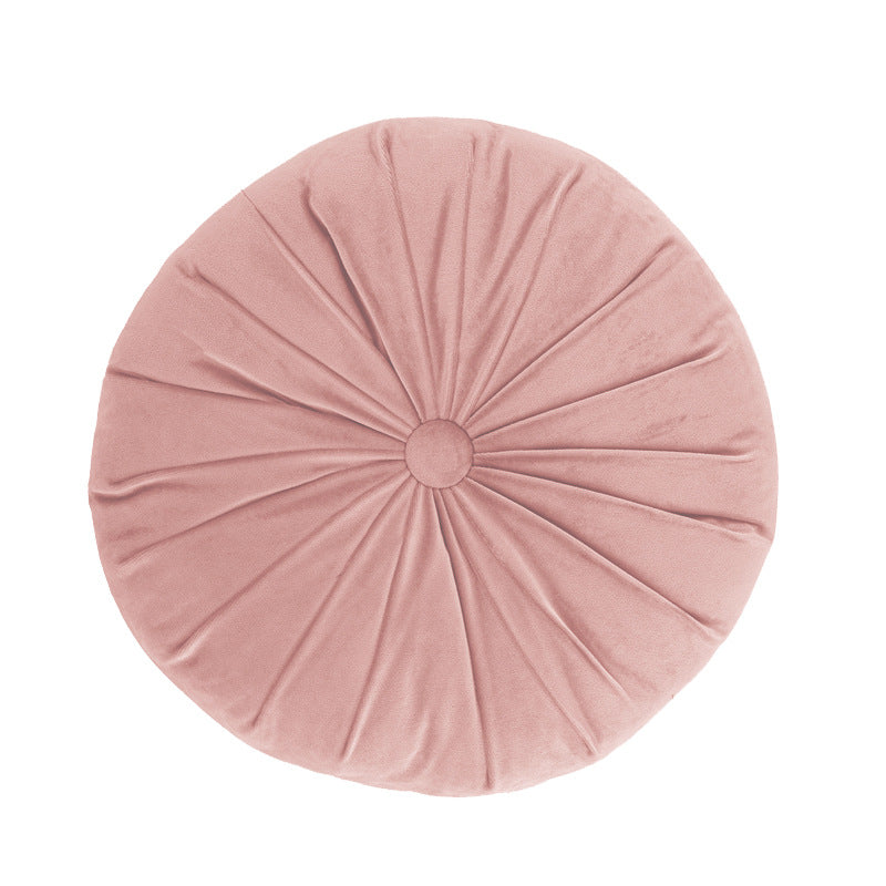 Round pink cushion with pleated texture on a white background