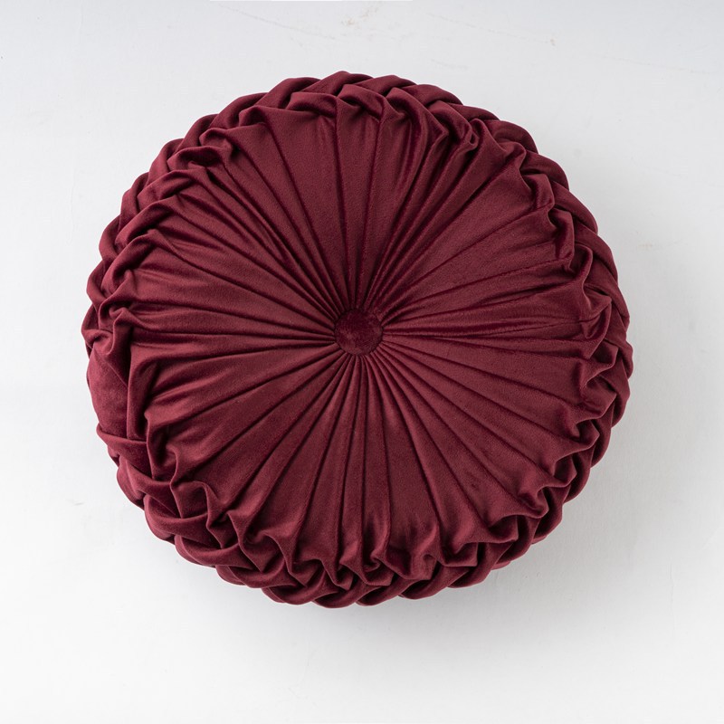 Round pleated burgundy cushion on a white background
