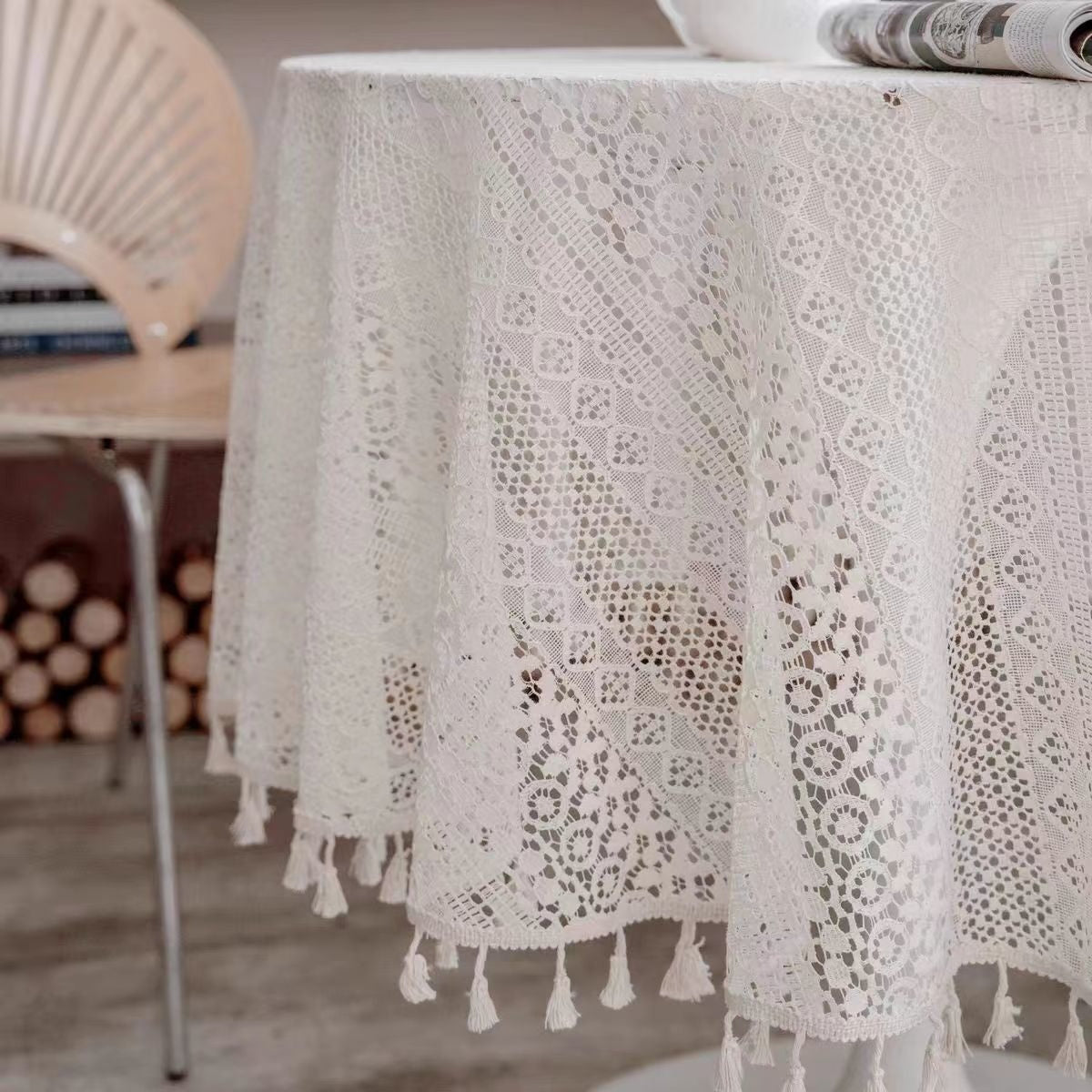 Round table with a lace tablecloth and tassels, set against a rustic background.